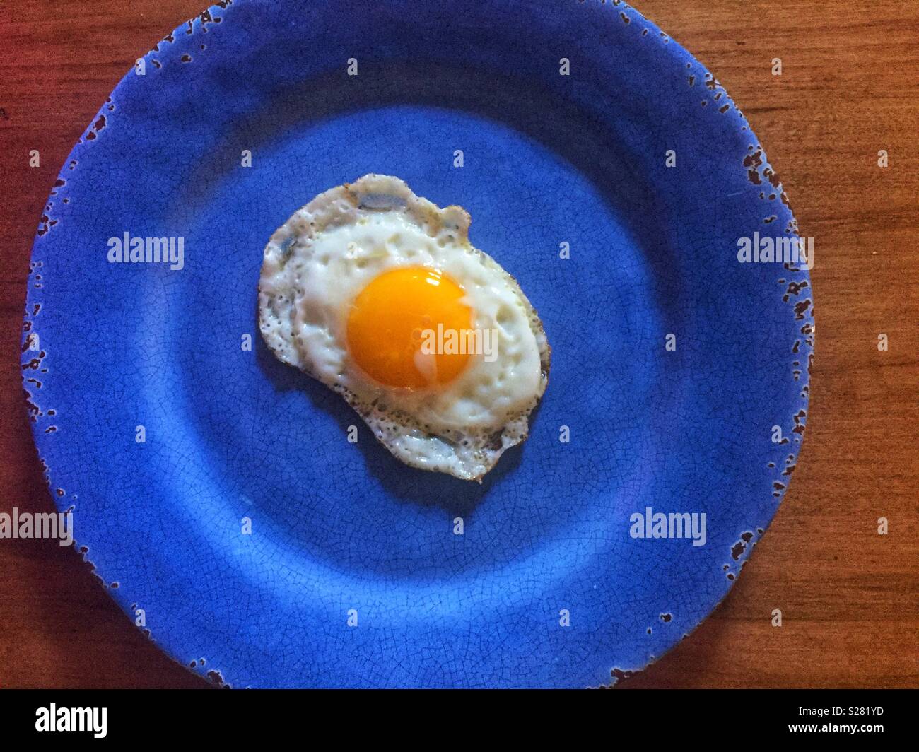 Single fried egg on blue plate Stock Photo