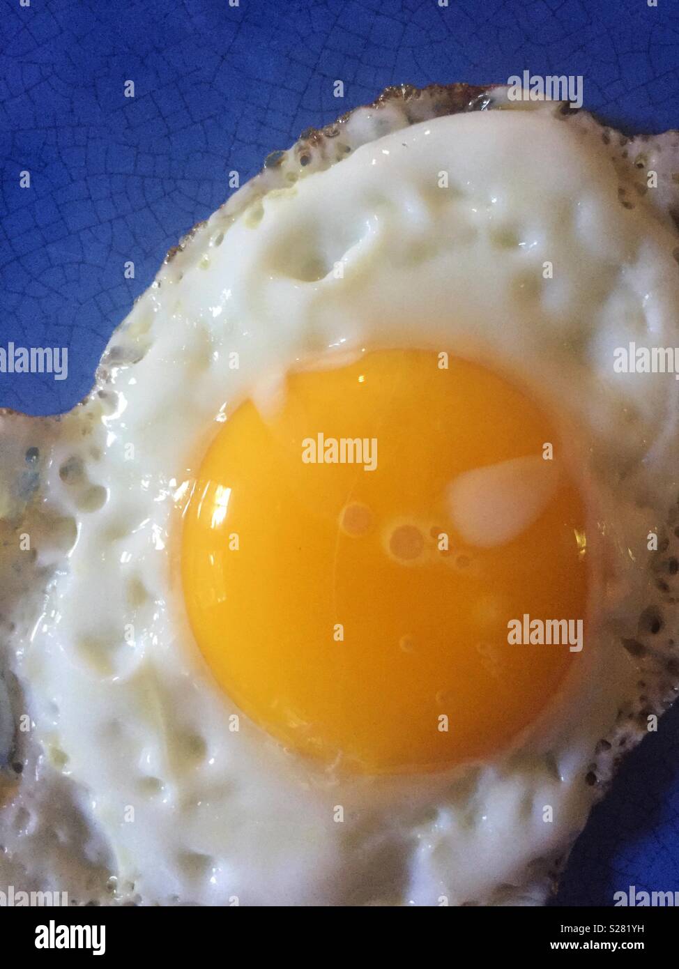 Closeup of fried egg on blue plate - Smartphone Captured Stock Image