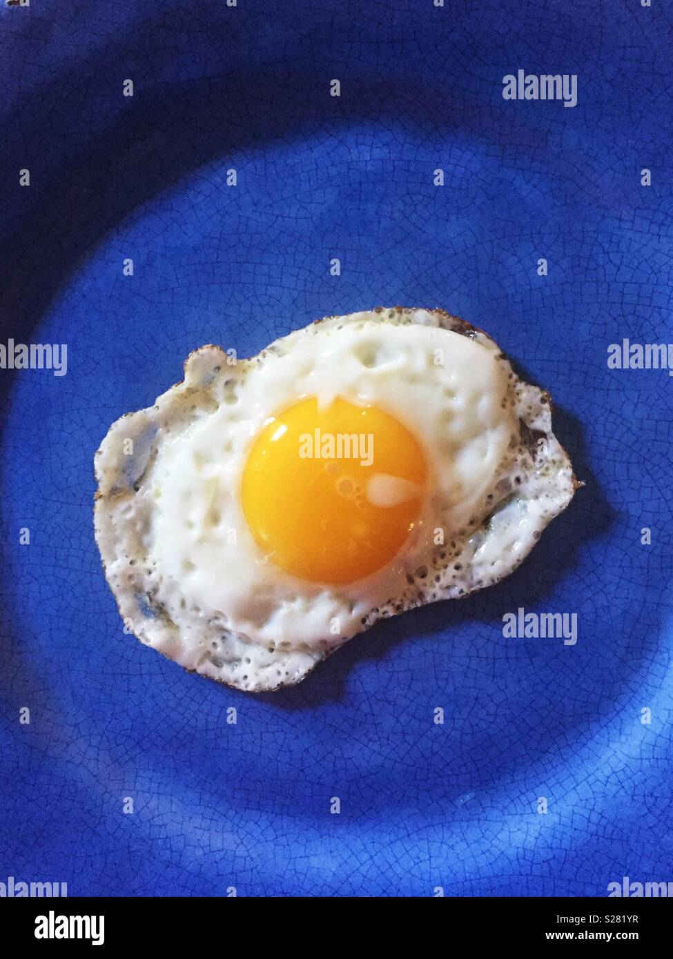 Fried egg on blue plate Stock Photo