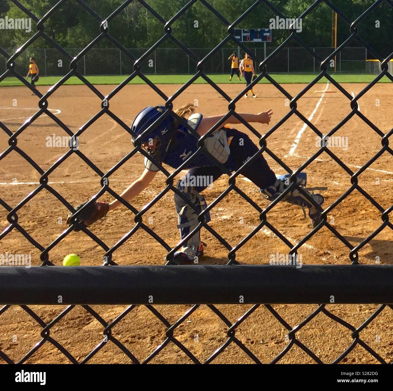 Catcher chasing ball.  Girls softball league Stock Photo