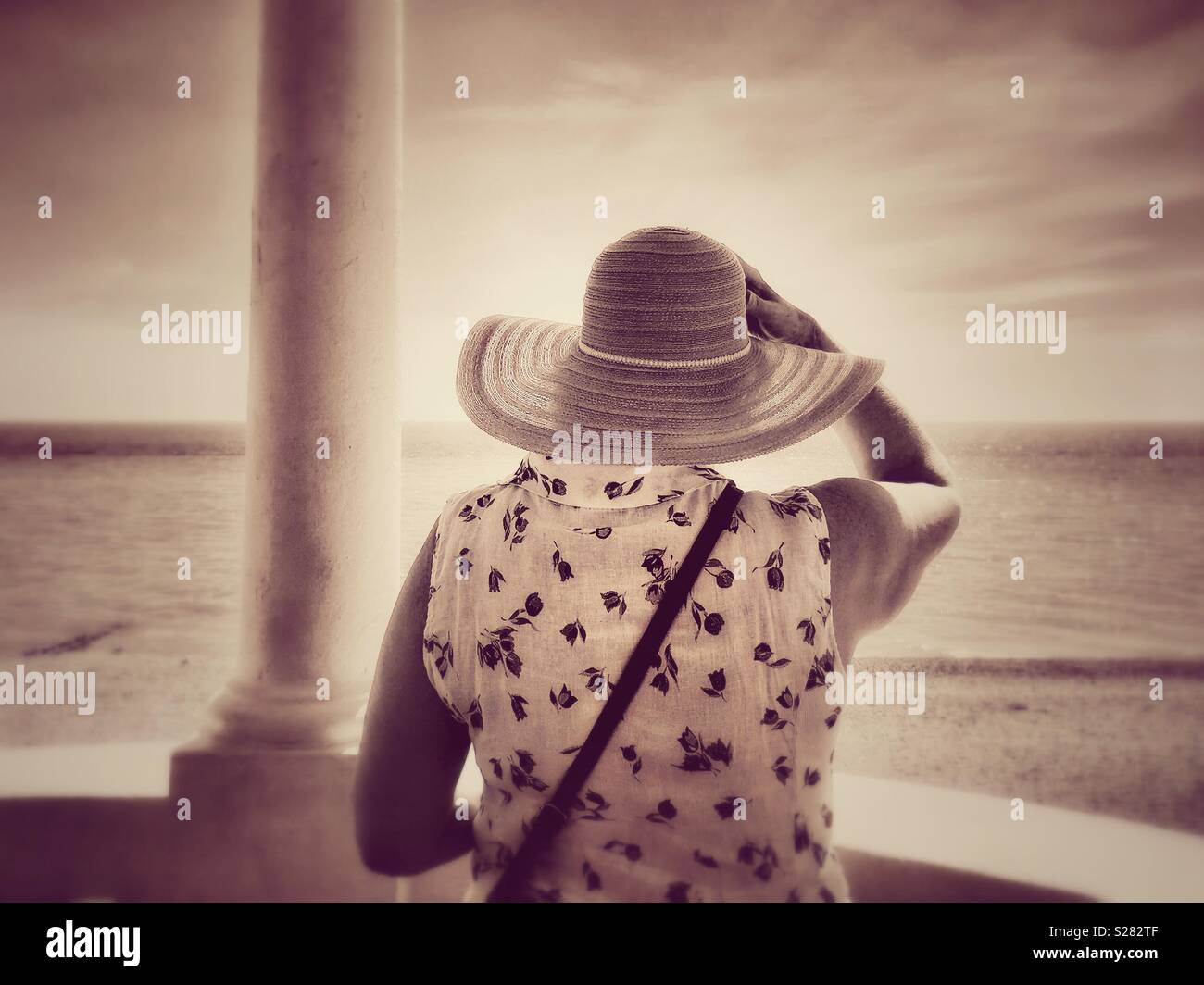 A woman in a hat looking out to sea. - Smartphone Captured Stock Image