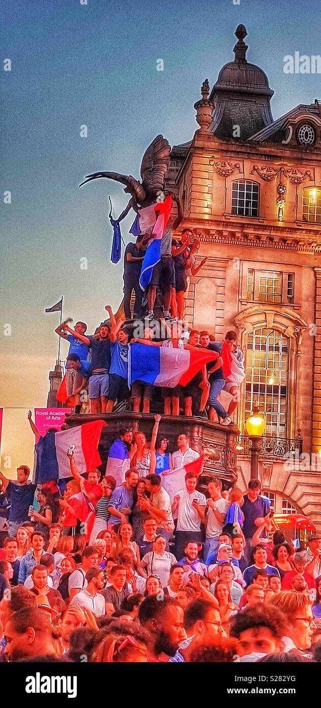 French football fans with Tricolour on Eros statue at Piccadilly Circus to celebrate France’s 2018 World Cup win, London - Smartphone Captured Stock Image