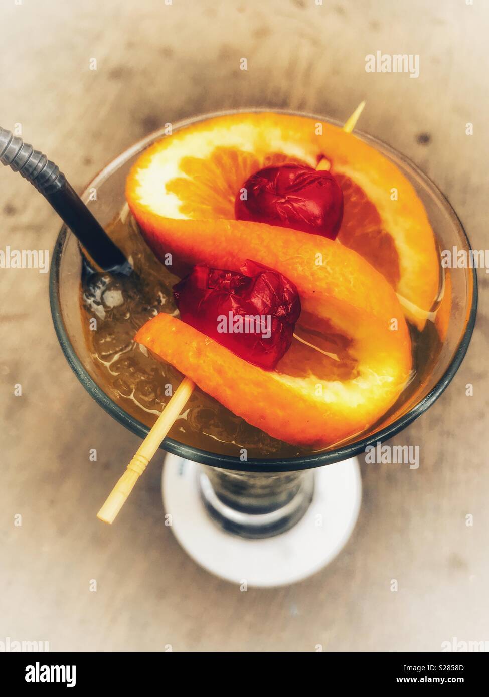 Cocktail, in a cocktail glass with a twist of orange and two cherries, high angle view Stock Photo