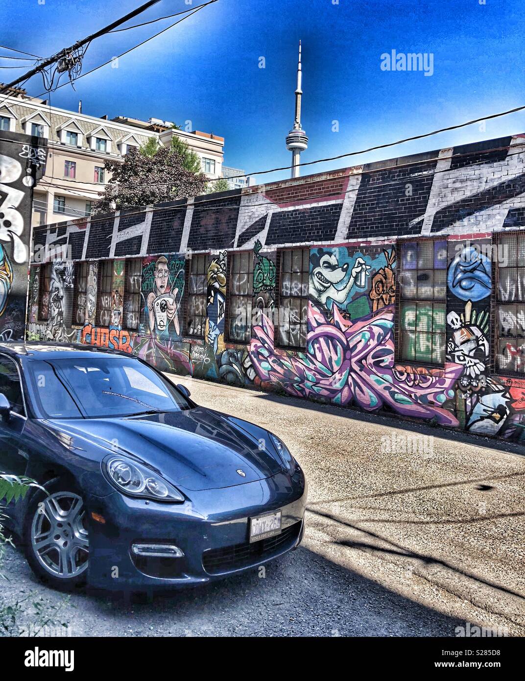 A Porsche parked in graffiti alley in Toronto with a view of the CN Tower in the background. - Smartphone Captured Stock Image