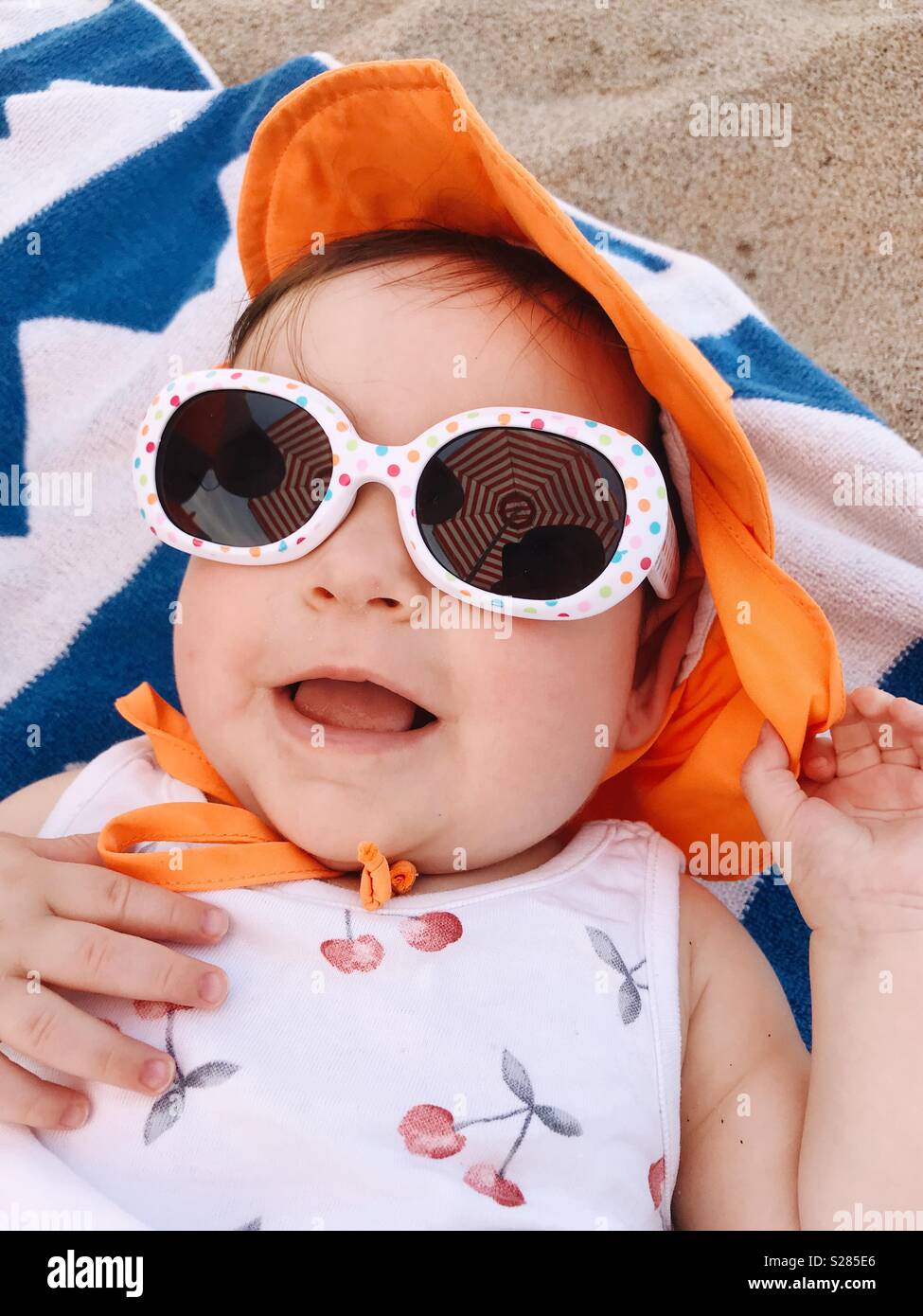 A young baby girl wearing sunglasses on the beach in Connecticut, USA. Stock Photo