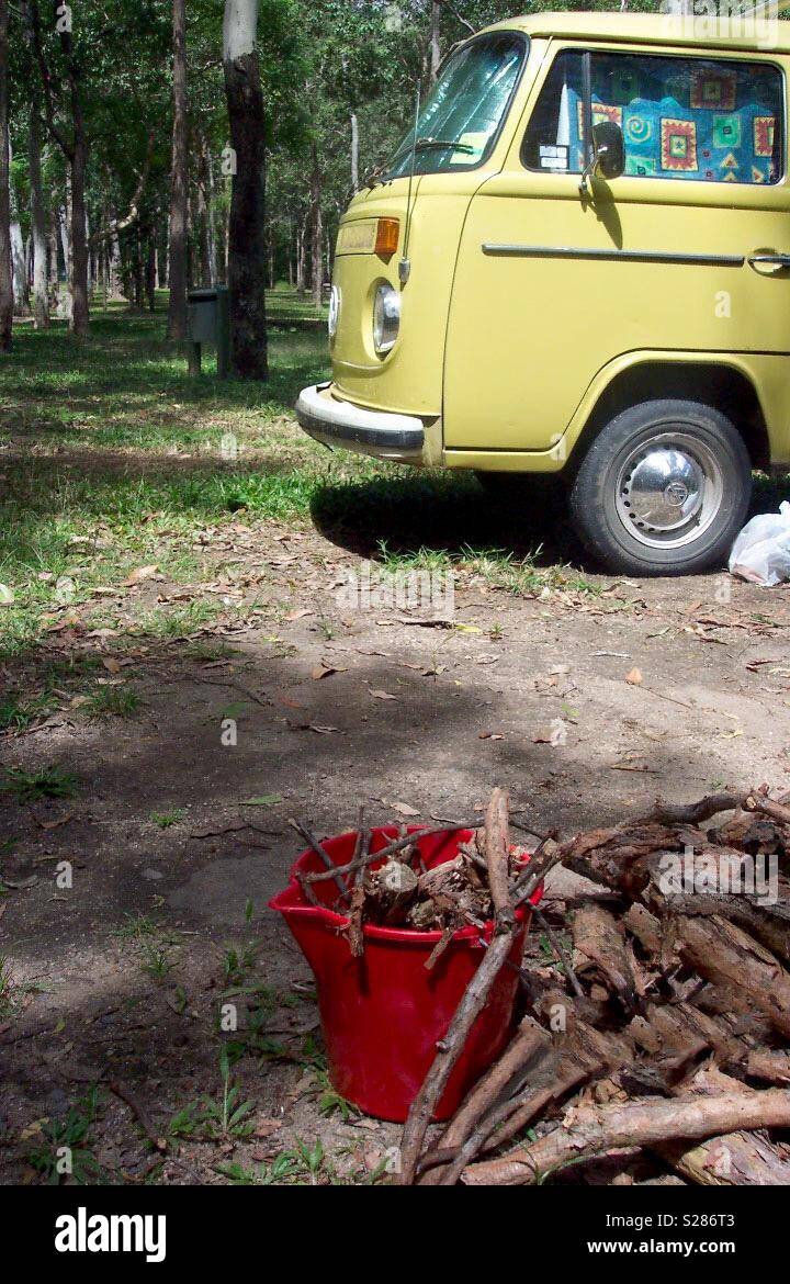 VW Kombi in Australian National Park beside bucket of wood for the campfire. Stock Photo