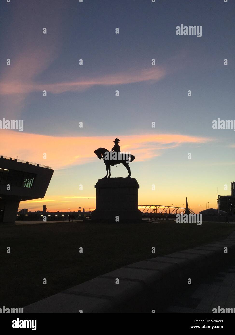 Silhouette of Statue at Albert Dock, and Museum of Liverpool against setting sun Stock Photo