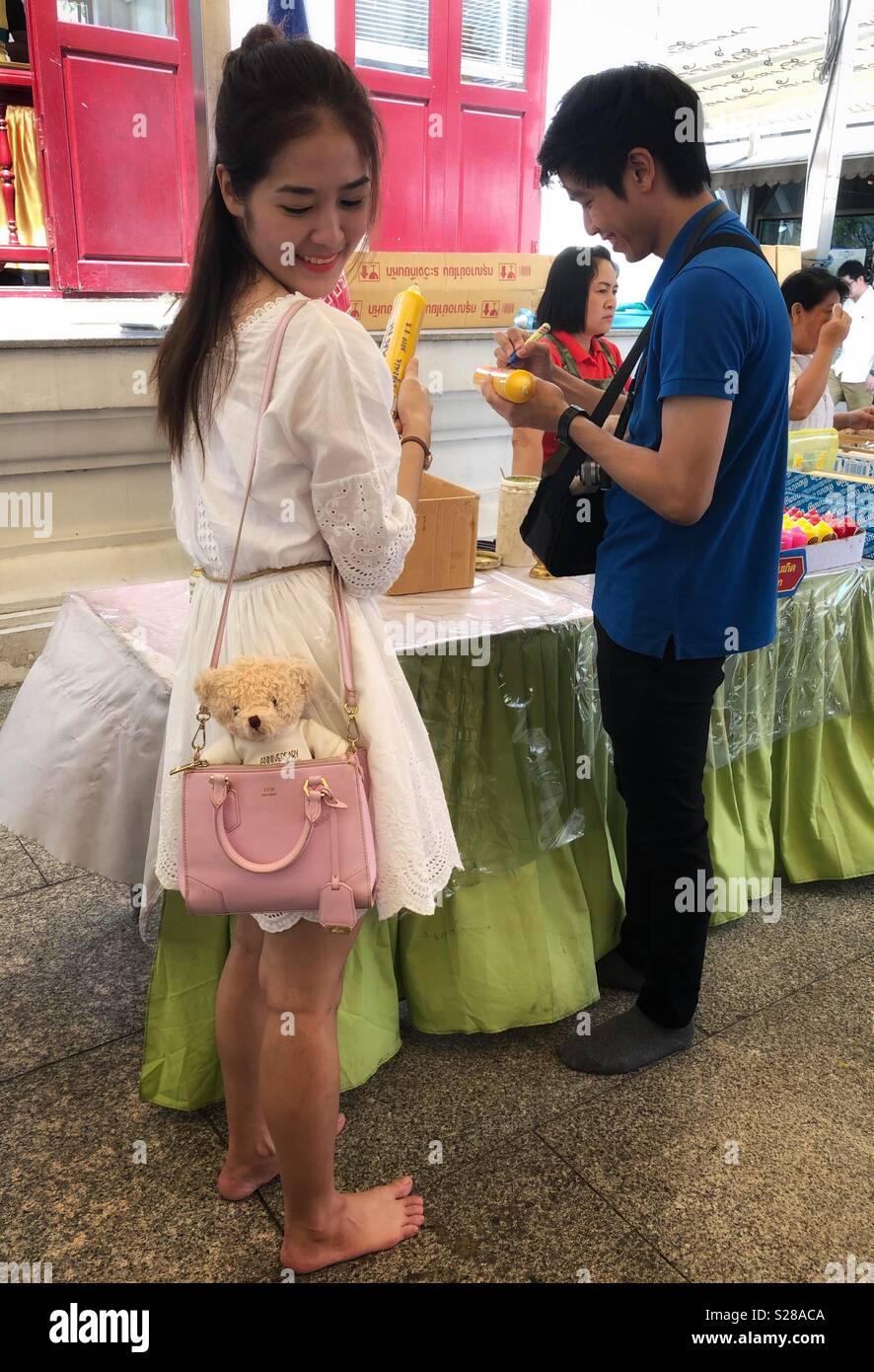 A stuffed teddy bear tags along in a young woman’s purse. - Smartphone Captured Stock Image