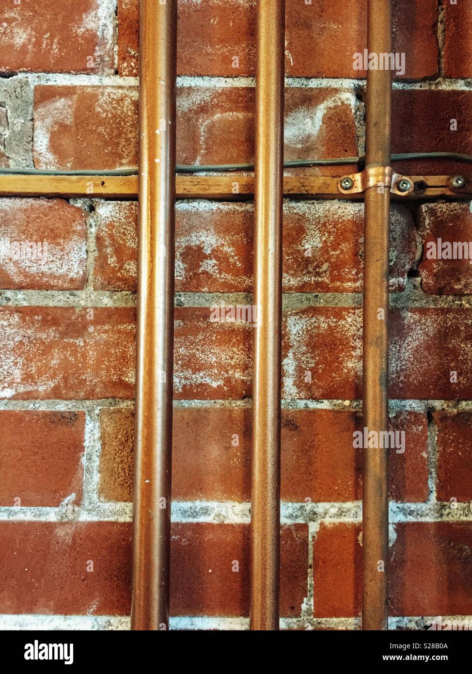 Copper pipes and old brick wall Stock Photo