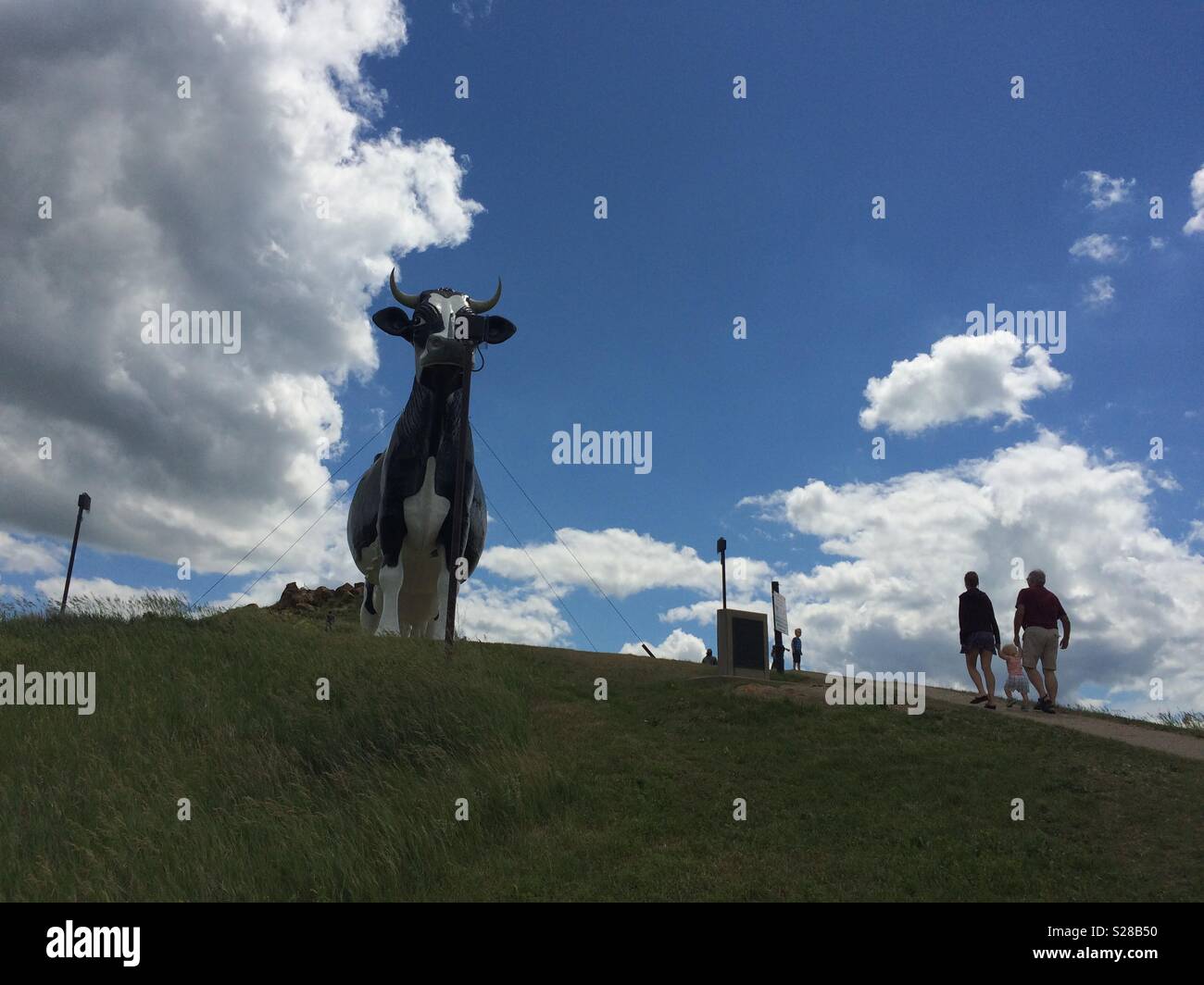 Family walking up towards giant cow statue in New Salem, North Dakota