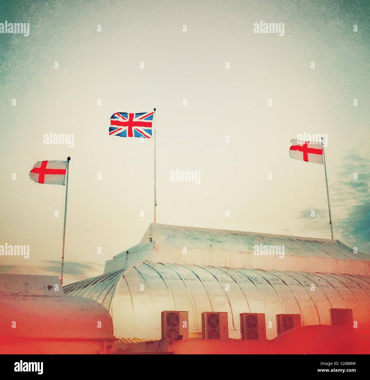 The flags of St George and the Union Jack fluttering in the wind on top of the pier at Burnham-on-Sea, Somerset - Smartphone Captured Stock Image