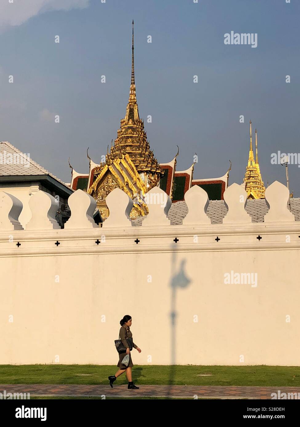 Woman walks by a temple in Bangkok, Thailand. - Smartphone Captured Stock Image