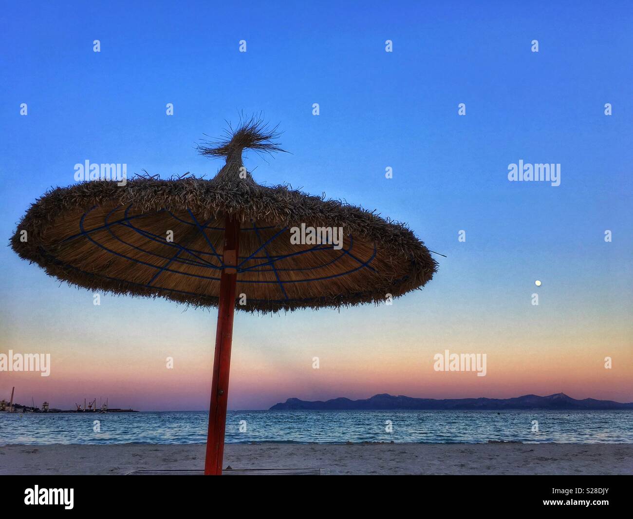 Straw beach  sunshade in silhouette against sky at dusk Stock Photo