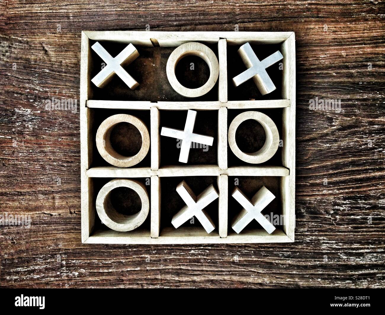 Wooden Noughts and Crosses or Tic-Tac-Toe game on wooden tabletop; crosses win. Stock Photo