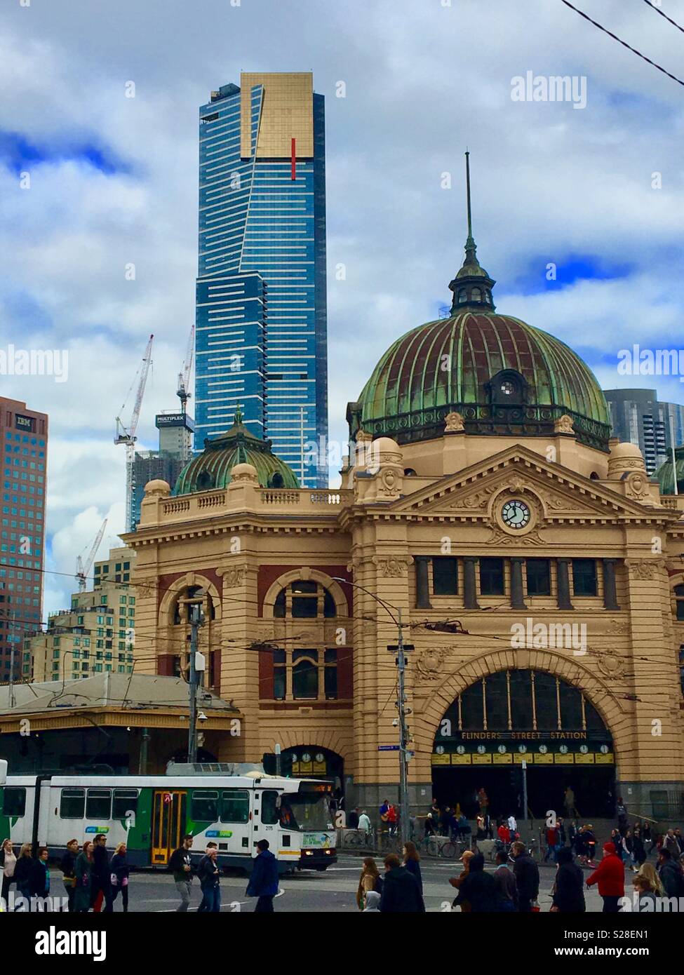 Flinders Street Station with Eureka Skytower and tram with people crossing Flinders Street in Melbourne Australia Stock Photo
