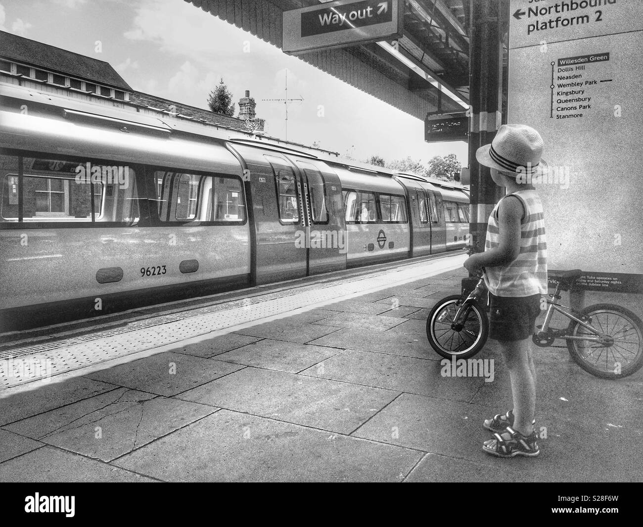 A boy with his bike looking at departing train, London, Kilburn station Stock Photo