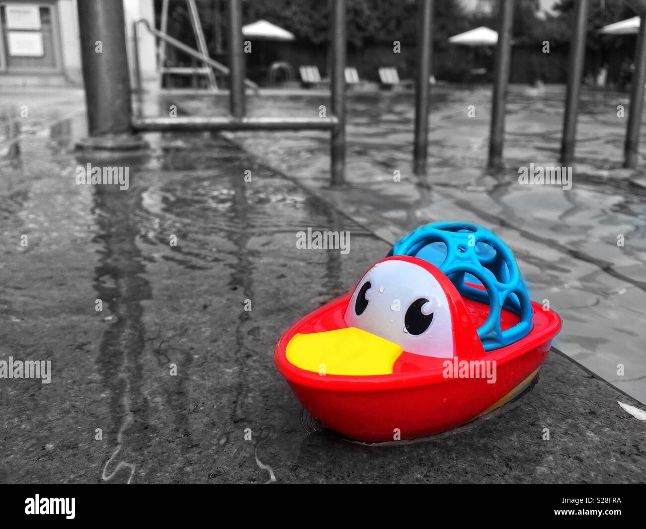 Black and white shot of a swimming pool with colorful plastic toy - Smartphone Captured Stock Image