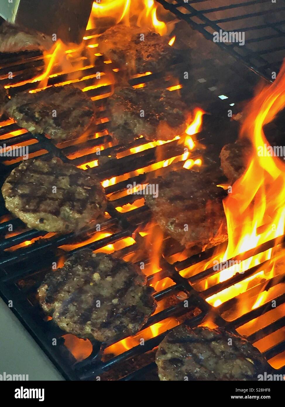 Hamburgers being cooked on a grill with open flames, USA - Smartphone Captured Stock Image