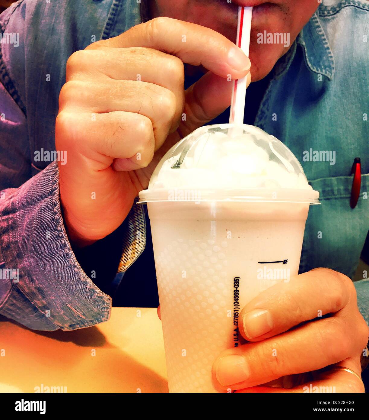 Man drinking milkshake through a straw, McDonald’s restaurant, USA - Smartphone Captured Stock Image
