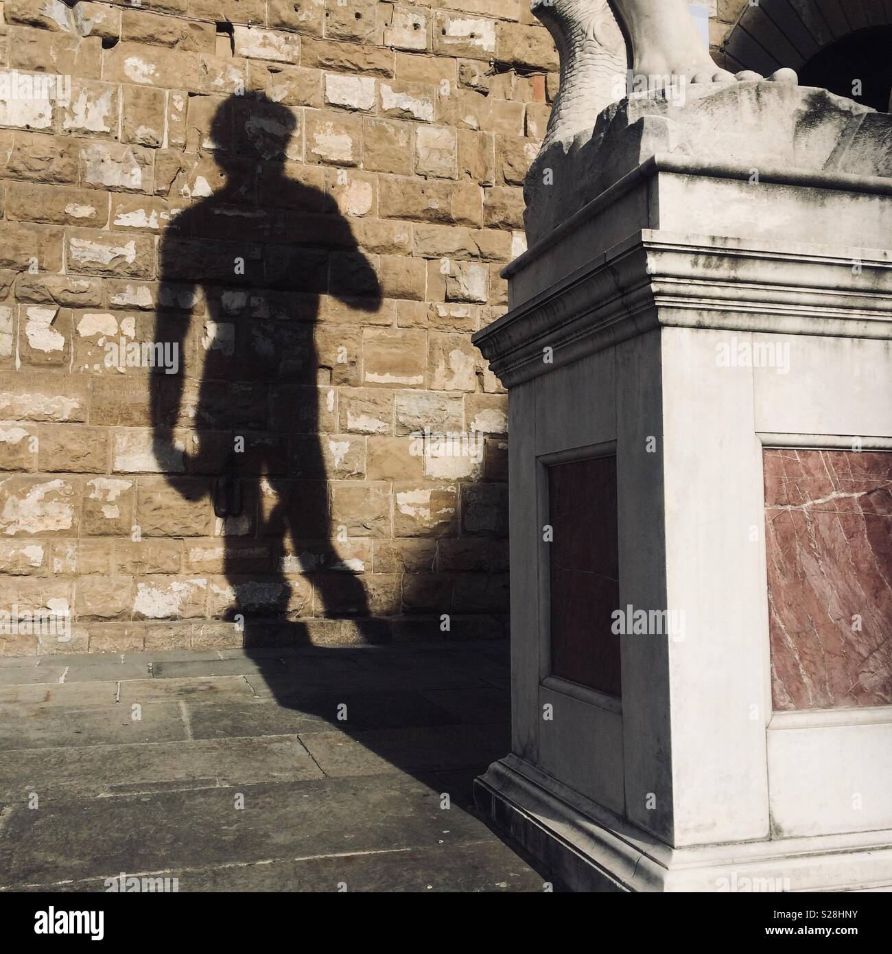 Shadow of Michel-Angelo’s David replica on the brick wall of Palazzo Vecchio, Florence, Italy Stock Photo