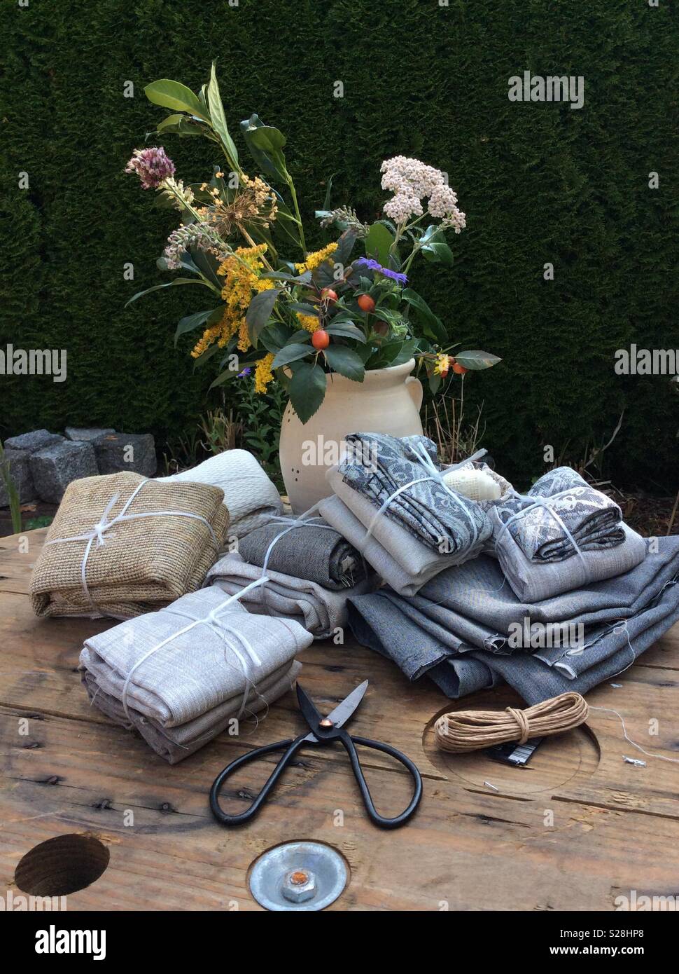 View on gift packages of vintage linen fabrics displayed on wooden cable roll in the garden Stock Photo