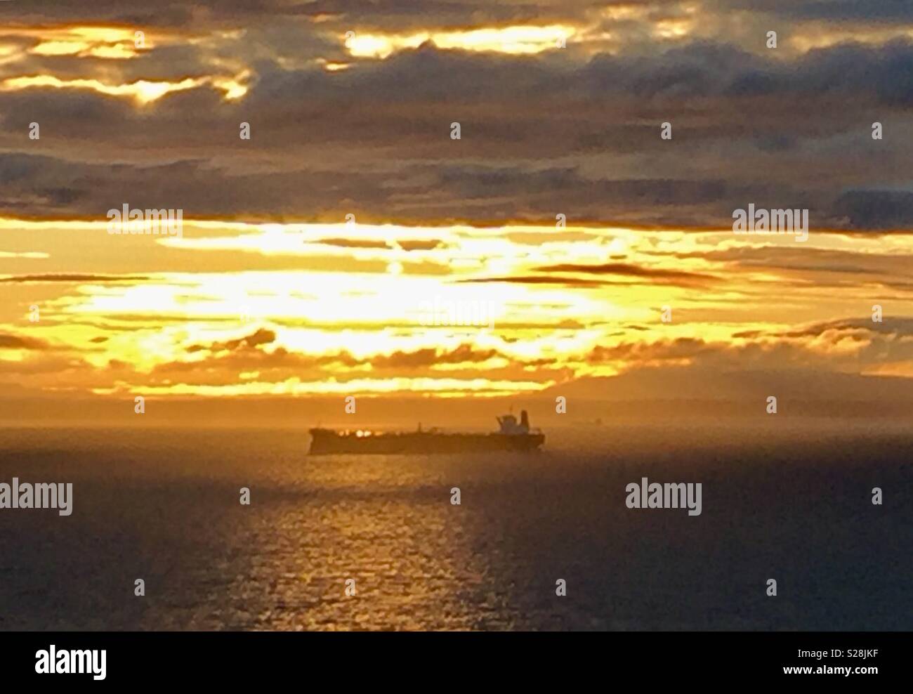 A massive tanker at anchor at sunset. Stock Photo