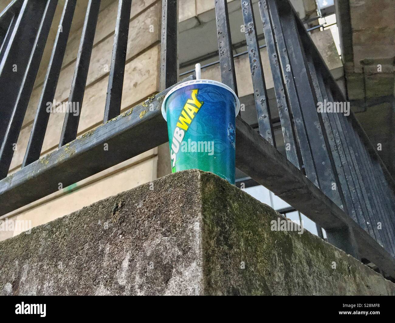 A paper cup abandoned on a stairway outside a brutalist building - Smartphone Captured Stock Image
