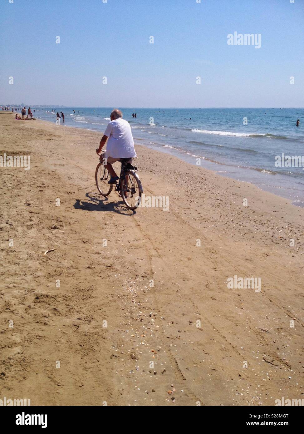 Old man cycling on Carnon beach, Mauguio, Occitanie France - Smartphone Captured Stock Image