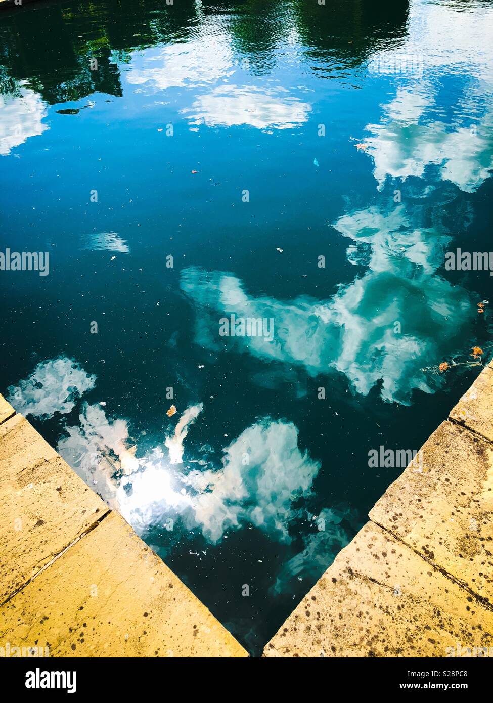 Clouds and blue sky reflections in a stone-edged pool - Smartphone Captured Stock Image