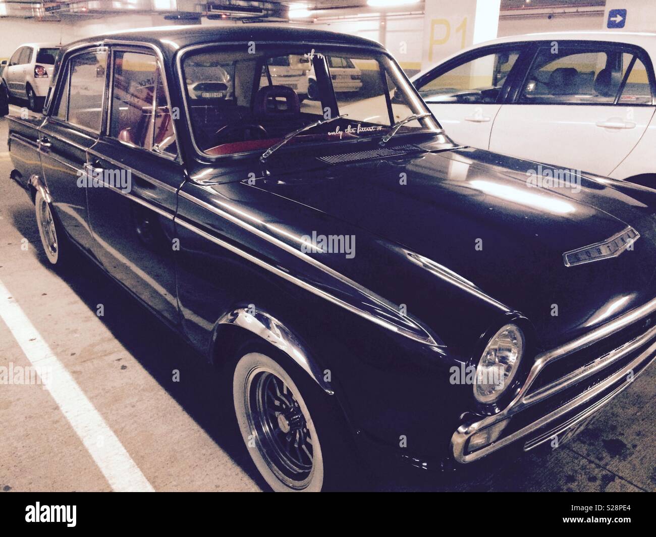 Retro style vintage black Cortina motor car parked in underground parking garage in city centre - Smartphone Captured Stock Image