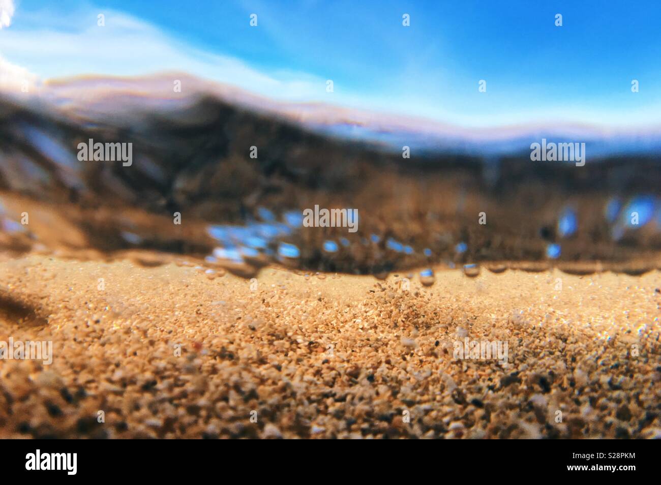 Sand underwater with blue sky above. Over under shot. Space for copy. - Smartphone Captured Stock Image