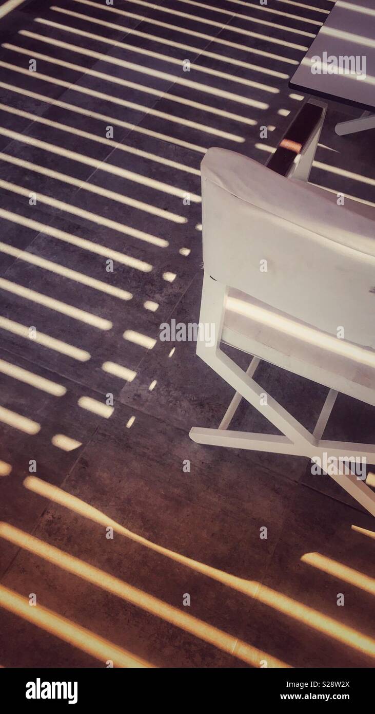 Chair and table in shade under a shuttered roof - Smartphone Captured Stock Image