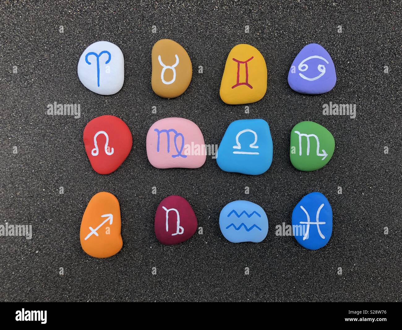 Astrological signs composed over black volcanic sand with colored stones - Smartphone Captured Stock Image