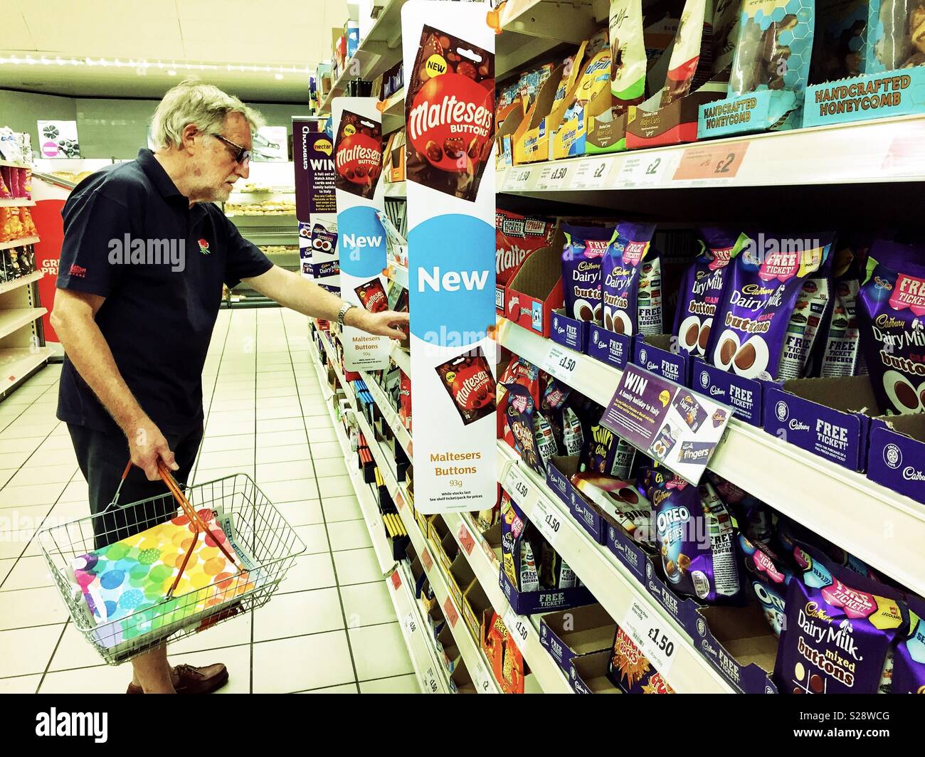 A man chooses chocolates at a supermarket. - Smartphone Captured Stock Image
