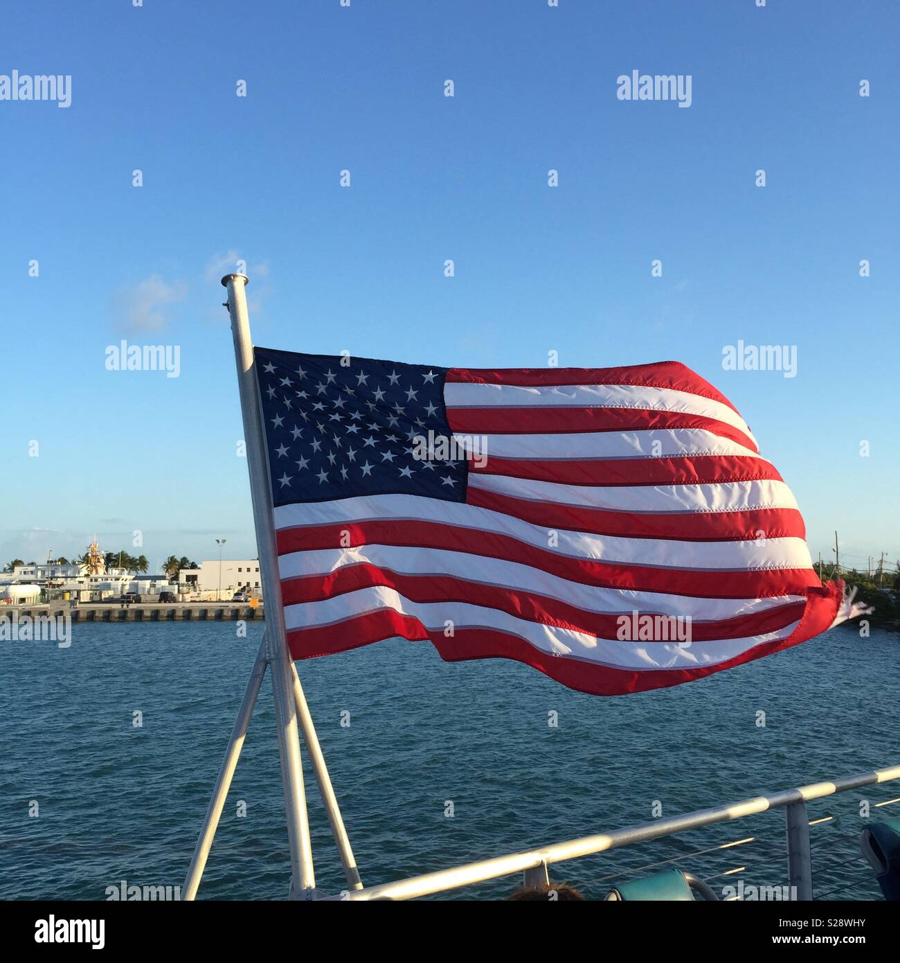 Key West, FL, USA. American flag flying on boat rail with view of Key West in background. Stock Photo