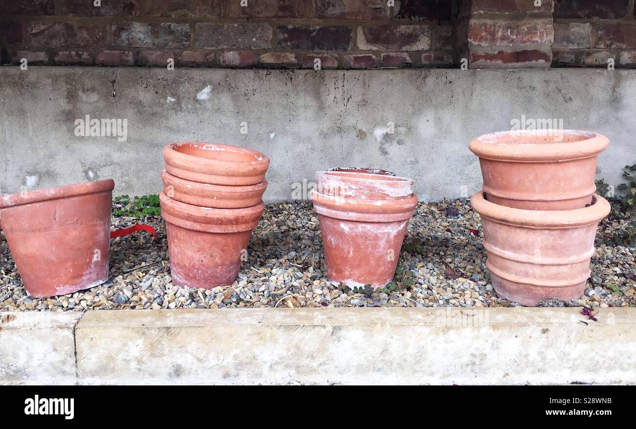 clay and terracotta plant pots stacked in rows inside a greenhouse in a gardening background Stock Photo