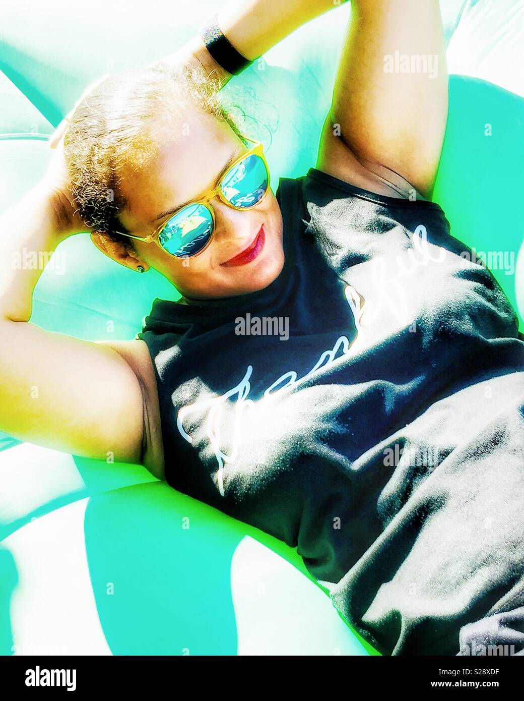A young woman relaxing in the sun. - Smartphone Captured Stock Image