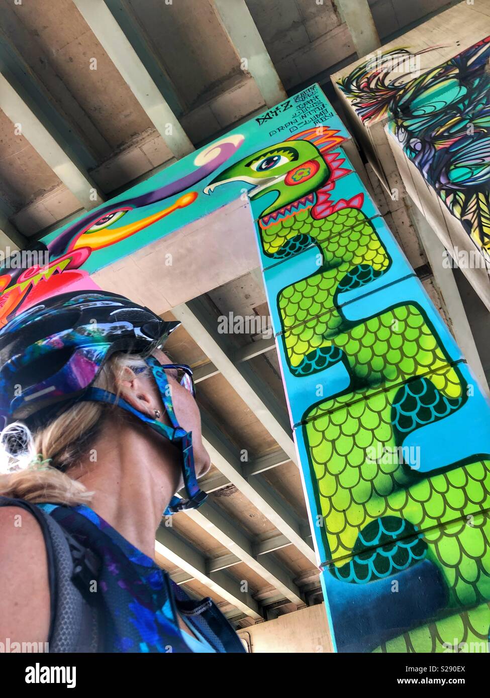 Woman looks up at a painted design on a pillar. - Smartphone Captured Stock Image