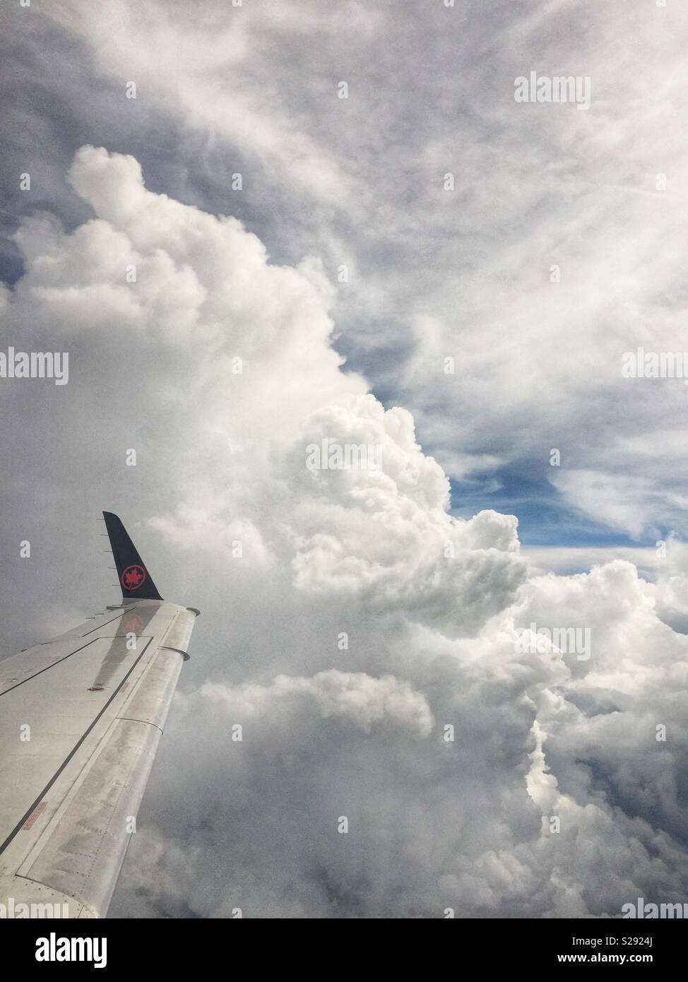 Air Canada Rouge flight from Newark, NY to Toronto navigates huge cumulus storm clouds during another hot and hazy afternoon on August 7, 2018. - Smartphone Captured Stock Image