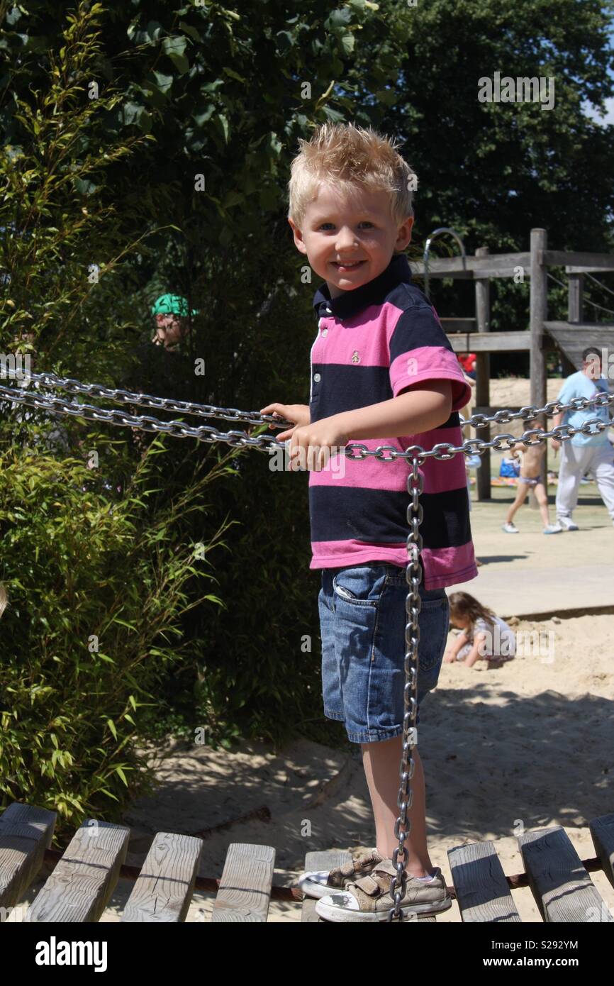 Little boy walking over a rope bridge in a playground Stock Photo