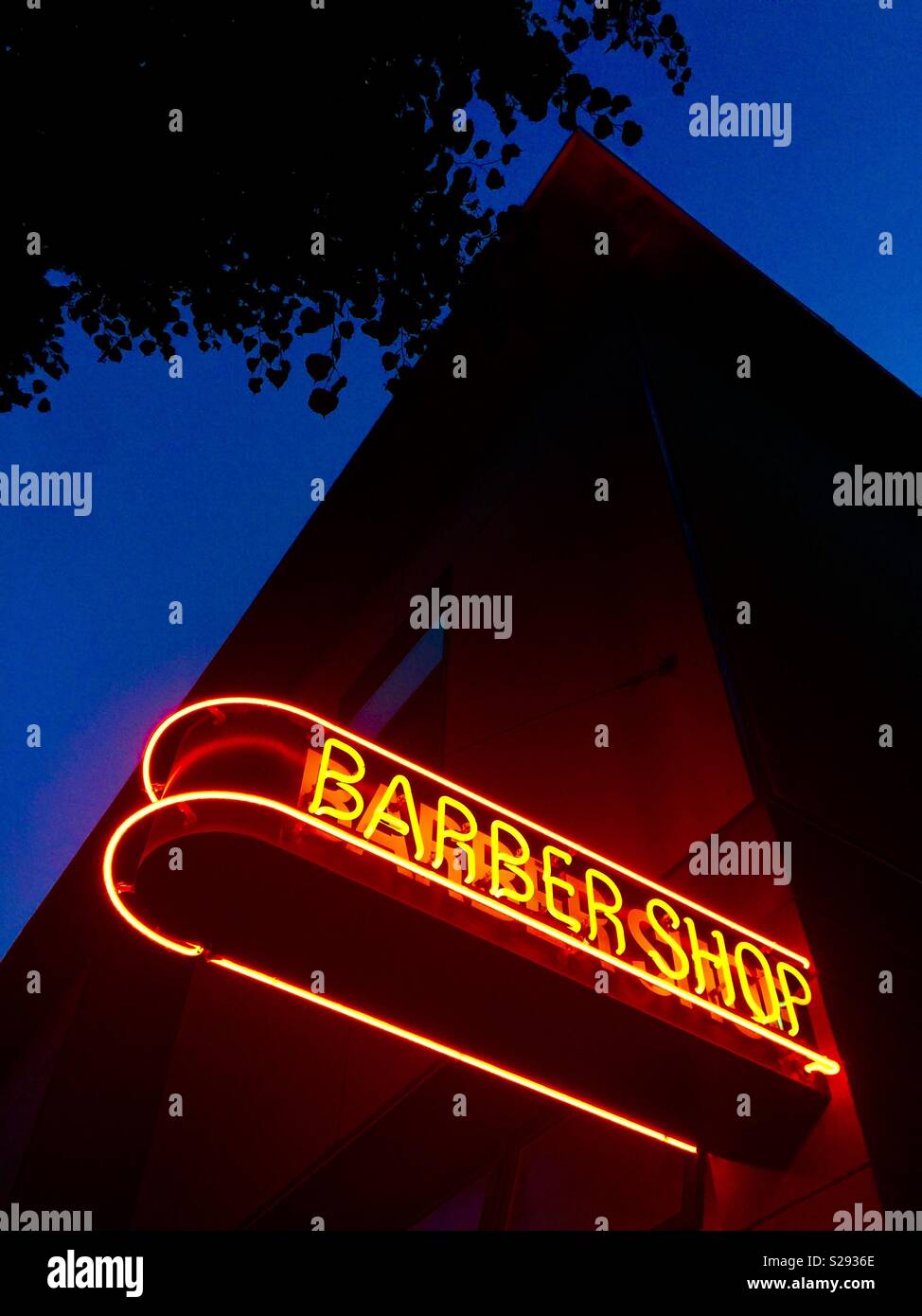 A mysterious lit neon barbershop sign at night Stock Photo
