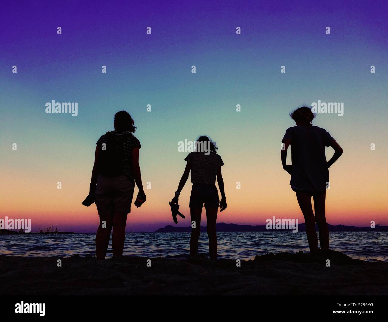 Family paddling in sea at dusk silhouetted against evening sky - Smartphone Captured Stock Image