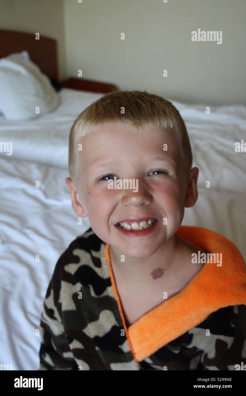 Boy sitting on bed wearing a dressing gown Stock Photo Alamy