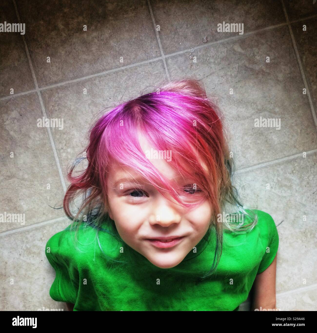 Small smiling girl with bright pink colored hair. Stock Photo