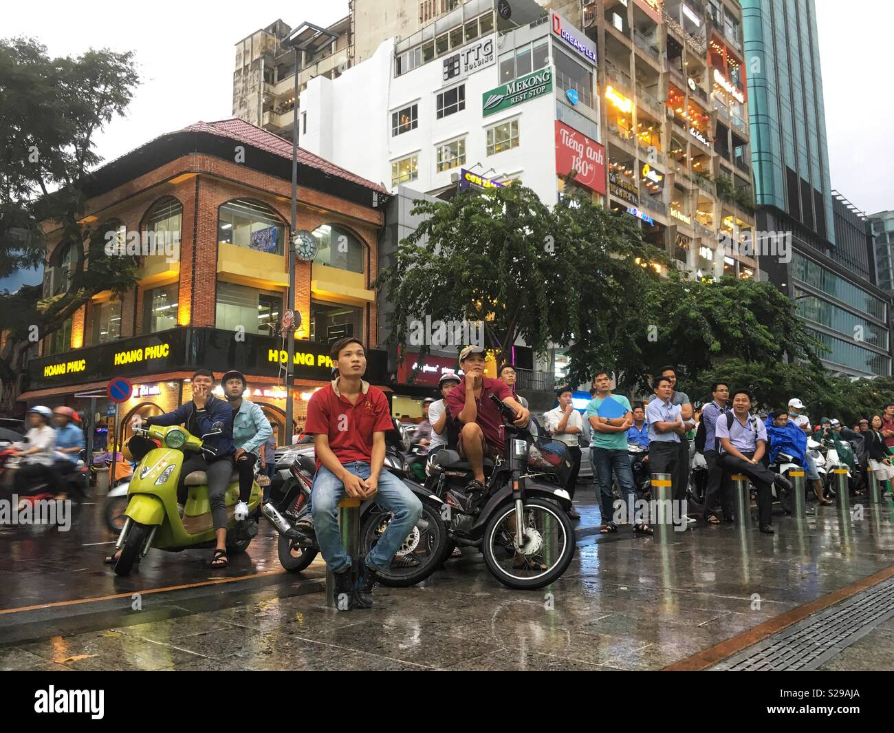 Ho Chi Minh City Vietnam motor scooter riders stop to watch a festival in the city centre - Smartphone Captured Stock Image