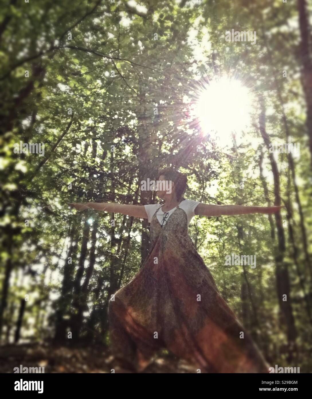 Woman practicing warrior Yoga pose in the forest Stock Photo