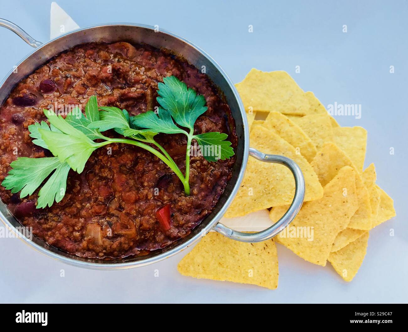 Homemade chilli con carne topped with coriander leaf with nacho chips