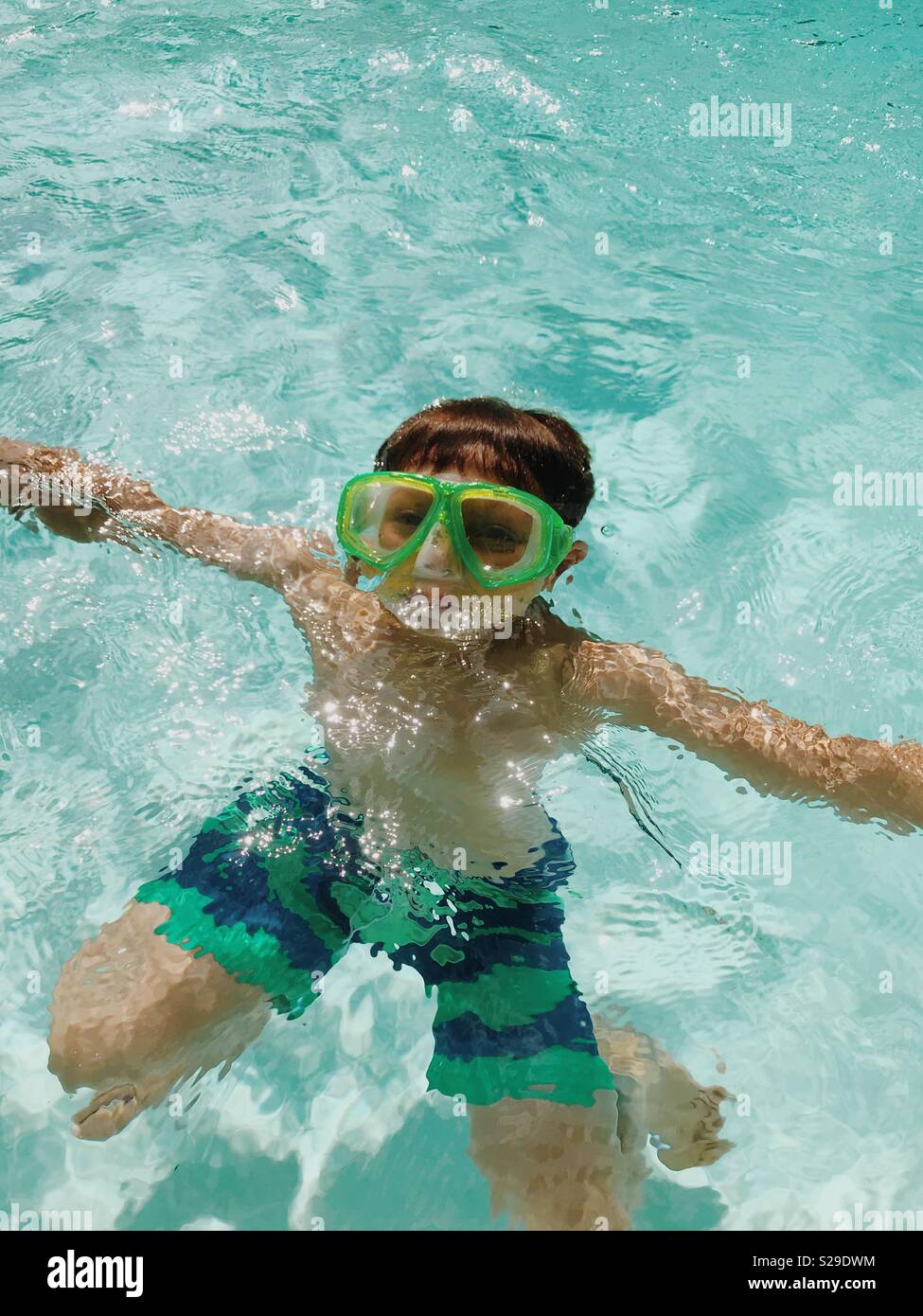 A young boy in a snorkeling mask underwater in an outdoor swimming pool. Stock Photo
