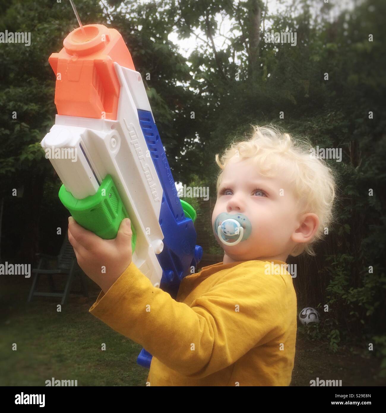 Two year old boy with a large super soaker water pistol. Stock Photo