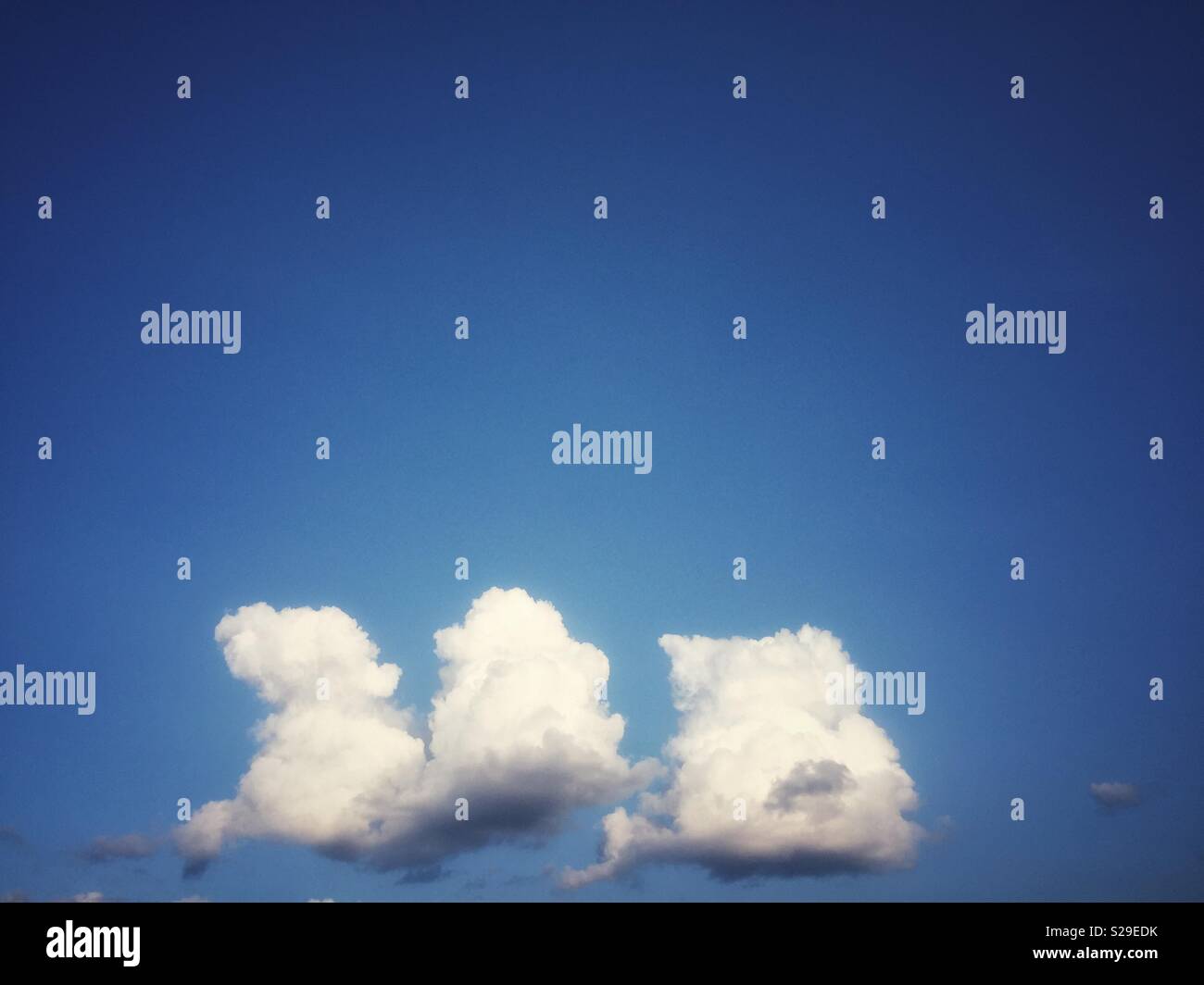 Three fluffy white clouds in a blue summer sky - Smartphone Captured Stock Image